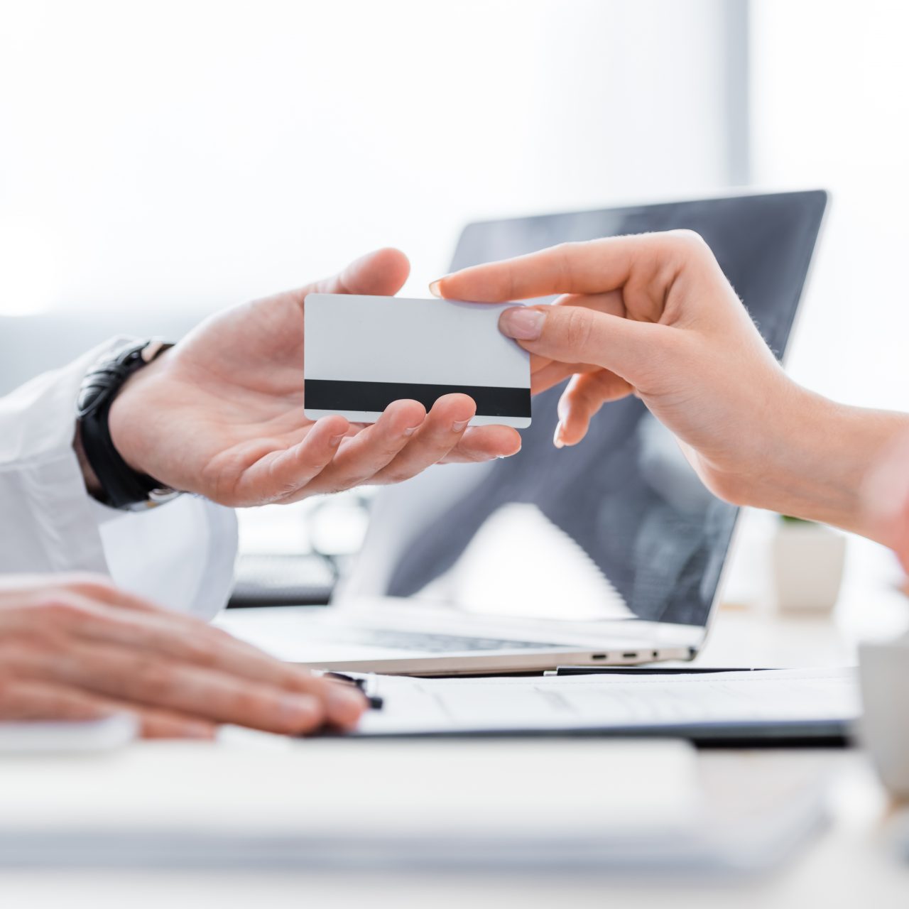 partial view of patient giving credit card to doctor in clinic